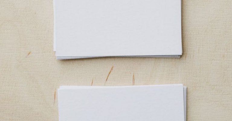 Mod Promotion - Top view of stacks of white mockup greeting cards placed on light wooden desk in soft daylight